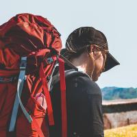 A pilgrim with a red backpack heads off.
