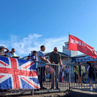 A Union Jack is draped over a railing, next to a red flag saying Jesus.