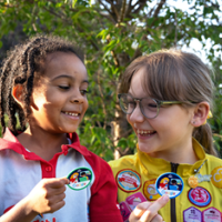 Two Brownies point out their badges.
