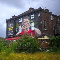 A mural on a side of a pub shows a footballer making a heart sign.