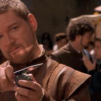 An Elizabethan man holds a dagger up while grinning.
