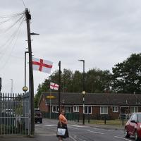 A suburban English street with St George's Cross flags on lamposts. 