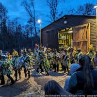 Wassailers emerge from a shed beside a wood