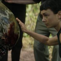 A young woman pets the head of an alien
