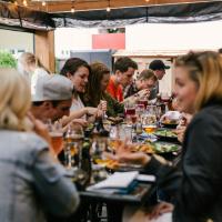 A group of friends sit arouns a large table eating together.